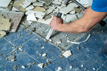 Worker remove, demolish old tiles in a bathroom with hammer and chisel - obrazy, fototapety, plakaty