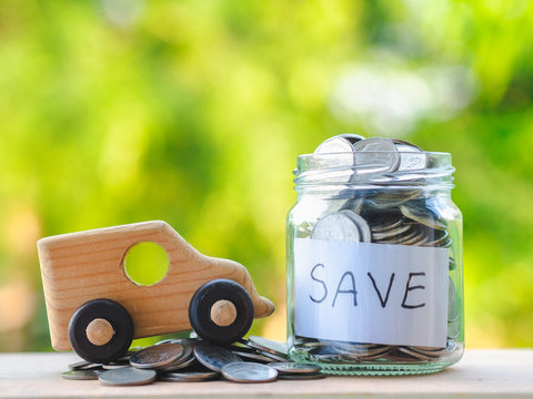 close up jar of coins and toy car on wooden table on blur background, saving money for car  and business concept