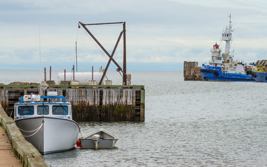 Boats docked and idle for the day, no people around, hot summer day on a wharf in a New Brunswick harbour.