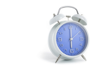 Twin bells analogue alarm clock with blue clock face shows six o’clock, 6 AM PM; concept on white background