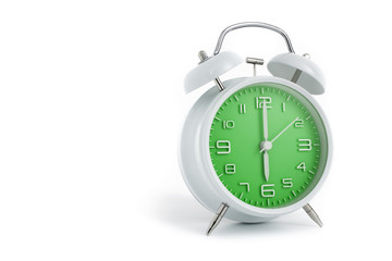 Twin bells analogue alarm clock with green clock face shows six o’clock, 6 AM PM; concept on white background