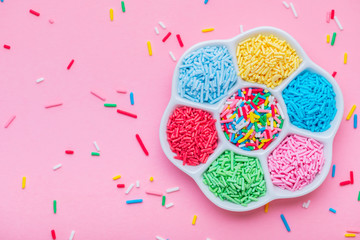 colorful sprinkles in plate over pink background, for decoration cake and bakery, copy space
