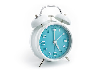 Twin bells analogue alarm clock with turquoise clock face shows five hours, 5 AM PM; concept on white background