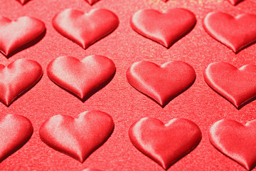 Fototapeta premium Closeup of a red heart on a shiny red background. The concept of love, choice and celebration of Valentine's Day. Selective focus.