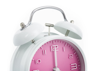 Cropped twin bells analogue alarm clock with pink clock face shows completed hour, concept on white background