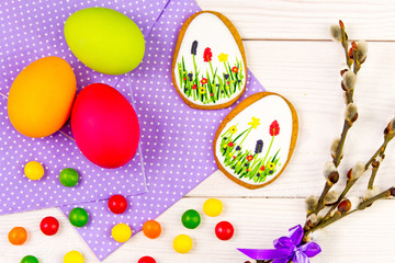 Easter background with Easter eggs and a willow twig. Easter gingerbread, eggs and willow twig on white wooden background. Easter Trend colors