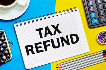 Notes Notebook with a TAX REFUND with the office tools on yellow blue background . Concept TAX REFUND