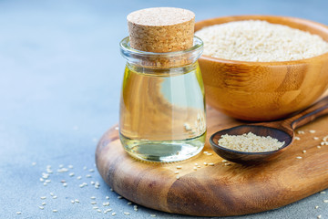 Organic sesame oil and sesame seeds in a wooden spoon.