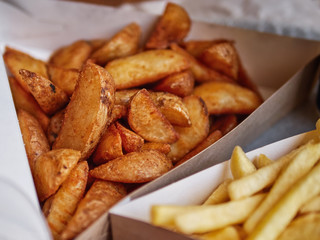 Plate of french and german fries and ketchup sauces on a table in fast food cafe.
