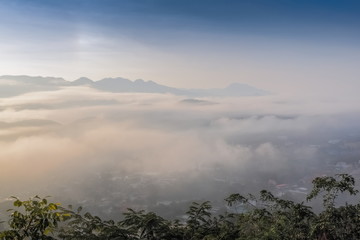 Top view misty morning above Mae Hong Son City, view of the sea of mist flood above city around with mountain and cloudy sky background, sunrise at Wat Phra That Doi Kong Mu, Mae Hong Son Thailand.