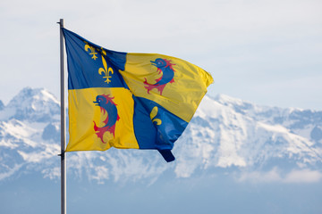 Grenoble, France, January 2019 : The Dauphine flag with snow covered Belledone mountains behind.