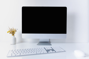 Clean and minimalistic office working place with desktop computer. Front view of PC, cell phone, papers and numeric keyboard on clean white table