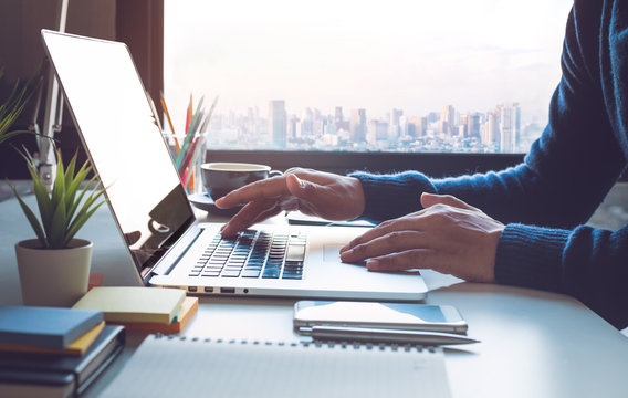 Young Businessman Working On Laptop In Office With Window City View.