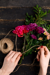 Fototapeta na wymiar Bouquet of flowers in female hand on a black wooden table