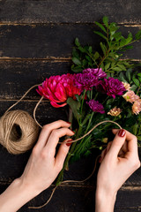 Fototapeta na wymiar Bouquet of flowers in female hand on a black wooden table