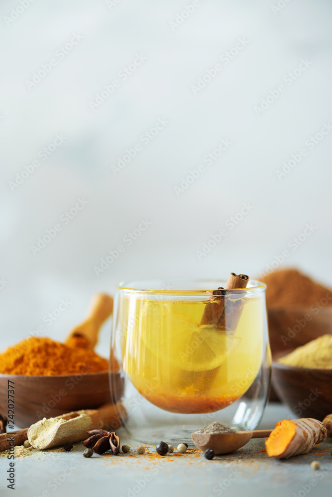 Wall mural ingredients for turmeric hot tea on grey background. healthy ayurvedic drink with lemon, ginger, cin