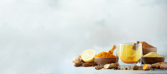 Ingredients for turmeric hot tea on grey background. Healthy ayurvedic drink with lemon, ginger,...