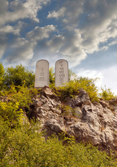 Ten Commandments List. Stone tablets on a rocky hill with carved 10 commandments - obrazy, fototapety, plakaty