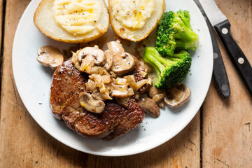 Steak with mushroom sauce, baked potatoes, broccoli