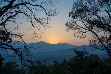 View of a sunset enclosed in a frame of trees to mean a concept of tourism