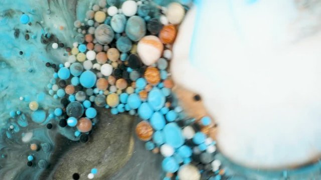 Colorful paint in bubbles organically moves in the liquid
