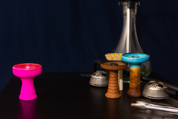 Hookah and four different hookah bowls and kalaud on the table close-up on a dark blue background