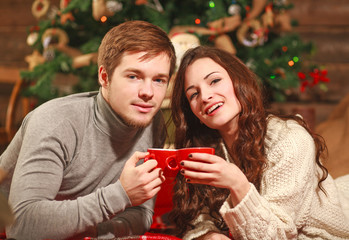 Young couple in love in a warm cozy home with cup of coffee in winter