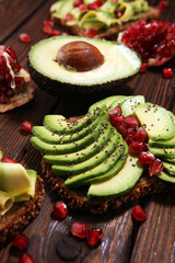 sliced avocado and ripe pomegranates on toast bread with spices and avocado.