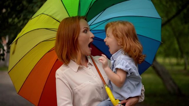 Happy mother and child under rainbow umbrella
