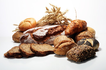 Different kinds of bread and bread rolls on board from above.
