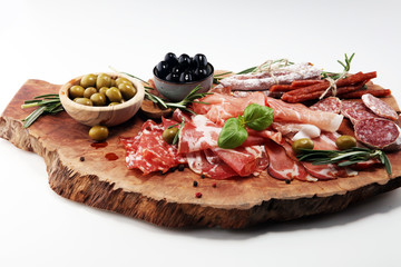 Marble cutting board with prosciutto, bacon, salami and sausages on wooden background. Meat platter