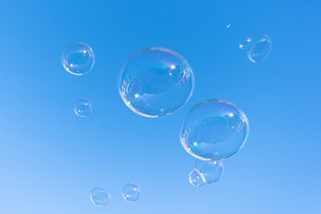 Soap bubble fly on blue sky background.