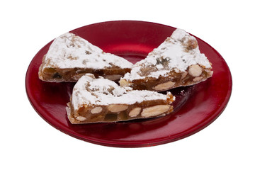 Panforte slices on red plate, isolated on white. Italian Christmas sweet dessert, cake make with dried fruits and nuts.
