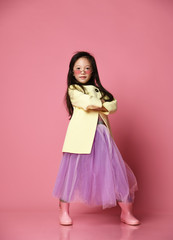 Little asian girl in yellow fashion jacket purple dress and modern red sunglasses posing