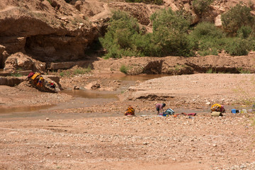 Mujer lavando montones de  ropa en el río en Marrakech