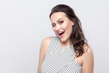 Portrait of funny happy beautiful young brunette woman with makeup and striped dress standing,...