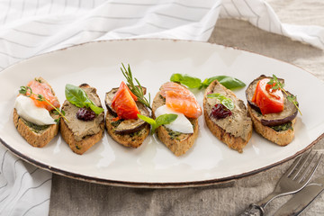 Brushetta set for wine. Variety of small sandwiches on white plate on the table