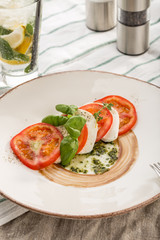 Delicious caprese salad with ripe tomatoes and mozzarella cheese with fresh basil leaves served on the table