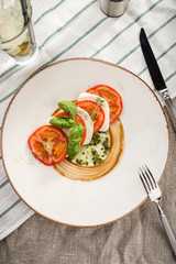 Delicious caprese salad with ripe tomatoes and mozzarella cheese with fresh basil leaves served on the table