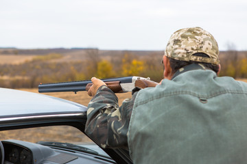 Hunter with a hat and a gun in search of prey in the steppe	