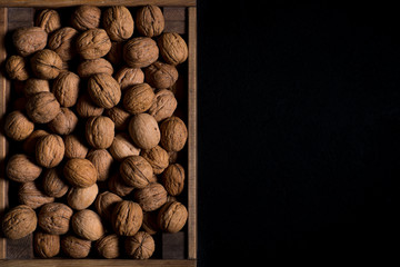 Walnuts in a wooden box on a dark background