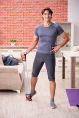 Young handsome man doing sport exercises at home 