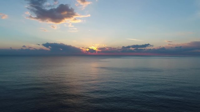 A footage of a sunset from above the sea via drone, clear water and colourfull clouds, 4k resoluted shooting