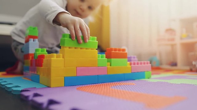 child playing with building blocks on the floor at home