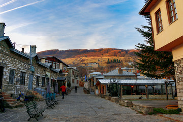 The central pedestrian street of the traditional village of Nymphaio . There are shops, the mountain with hotels and the clock with the sign with the destinations (square, church, museum)