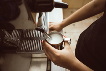 The barista is making boiled milk. He uses special coffee machine for it.