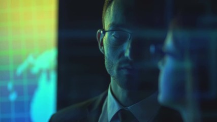 The businessman and a businesswoman in glasses discussing near the screen - Powered by Adobe