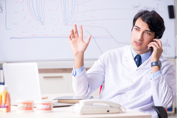 Young handsome dentist in front of the whiteboard 