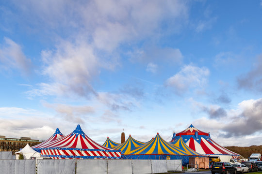 Red and white circus tents topped with bleu starred cover against a sunny blue sky with clouds