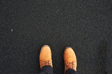 Explorers foot in the hiker boots on the black sand beach in Iceland, Europe. Aerial view. Concept of active lifestyle, travel and adventure lover.